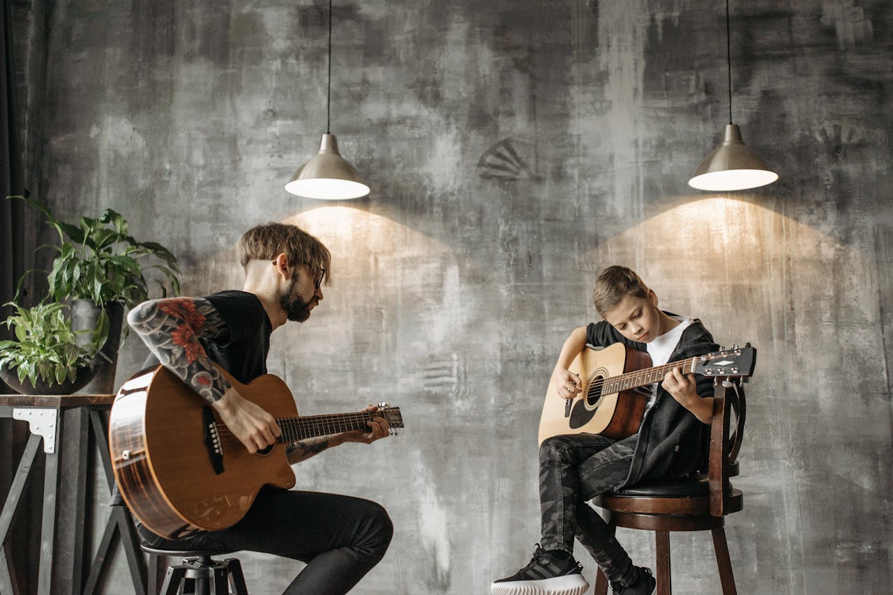pexels-photo-7520986 A child and adult participate in an indoor acoustic guitar lesson with a modern artistic backdrop.